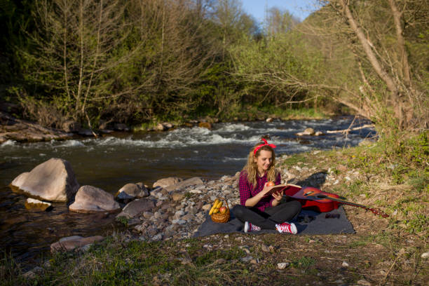 wanita duduk di tepi sungai dan membaca buku - reading book potret stok, foto, & gambar bebas royalti