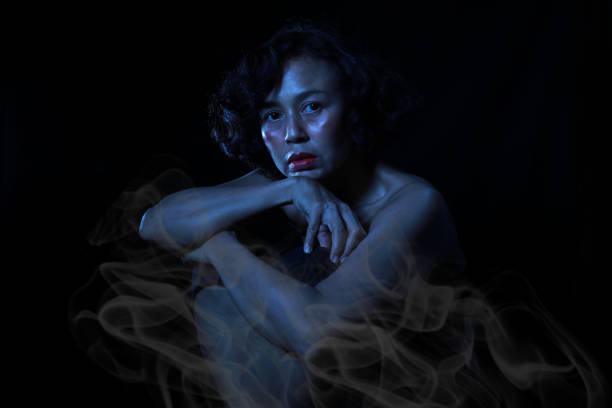 Woman sitting in the dark with smoke, Divine magic and occultism concept. stock photo
