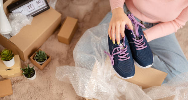 kvinna som sitter i vardagsrummet är glada över att öppna en ny paketlåda och skor från online shopping hemma för semester. - new standards bildbanksfoton och bilder