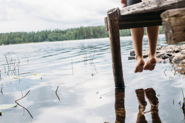 donna seduta su un molo - finlandia laghi foto e immagini stock