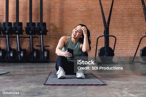 istock Woman sitting on exercise mat laughs with unseen person 1324103263