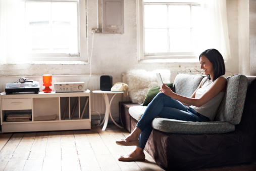 Woman sitting on sofa using digital tablet