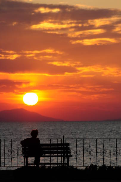 Woman sitting on the bench in Iznik Lake at sunset,Iznik,Turkey stock photo