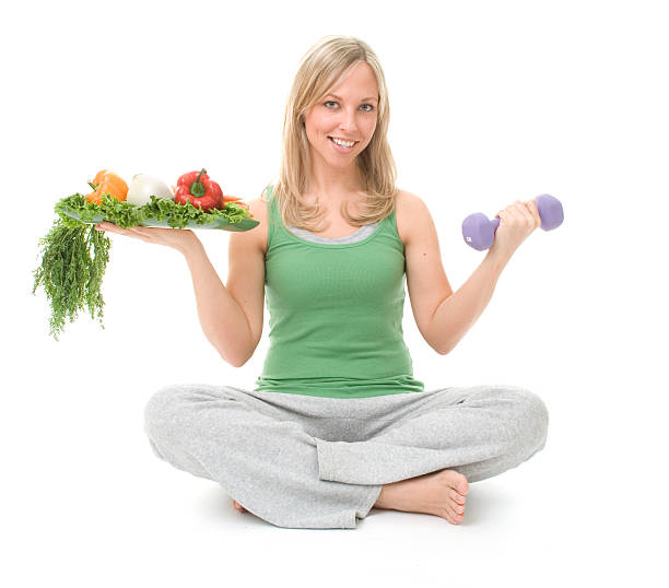 Woman sitting on the floor with weights and healthy foods stock photo