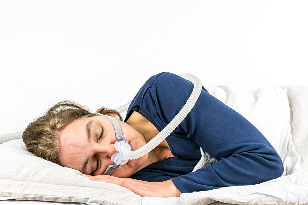 Woman sleeping on her side with CPAP, sleep apnea treatment. stock photo