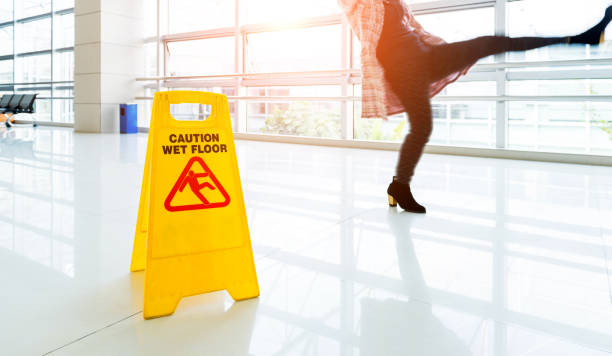 Woman slips next to the wet floor sign stock photo