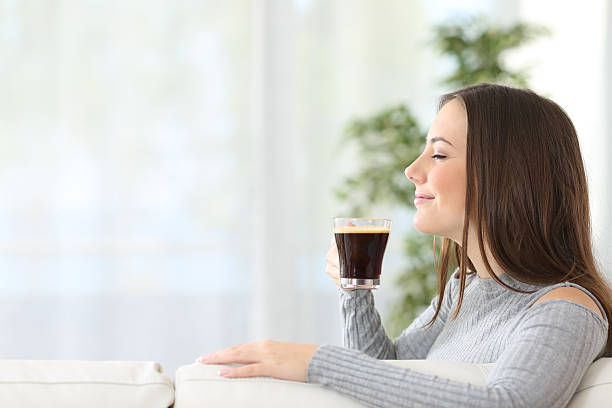woman smelling a cup of coffee at home - sniffing glass imagens e fotografias de stock