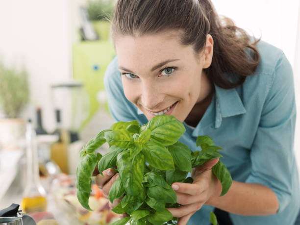 vrouw ruiken verse basilicum thuis - basil plant stockfoto's en -beelden