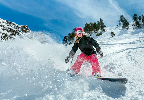 Woman snowboarder in motion in mountains stock photo
