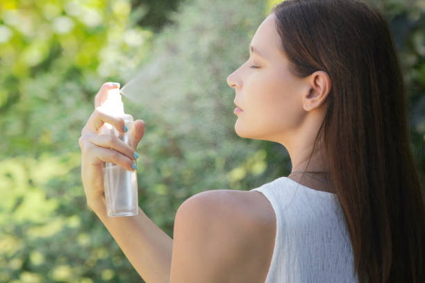 Woman spraying facial mist on her face, summertime skincare concept  spraying stock pictures, royalty-free photos & images