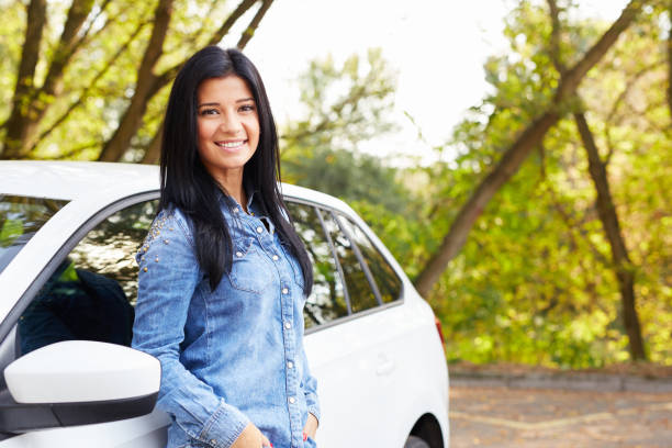 Woman standing by her car Young happy woman standing by her car with hands in pockets leaning stock pictures, royalty-free photos & images