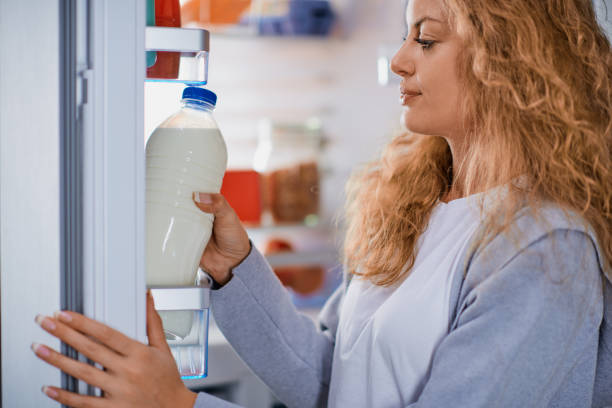 Woman standing in front of fridge and taking milk. stock photo