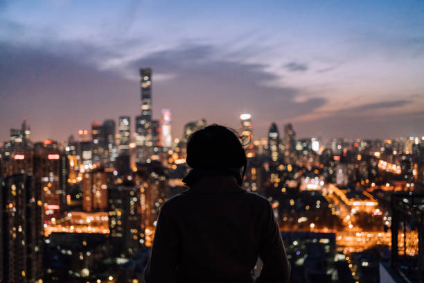 Woman Standing in Front of Modern City at Night stock photo