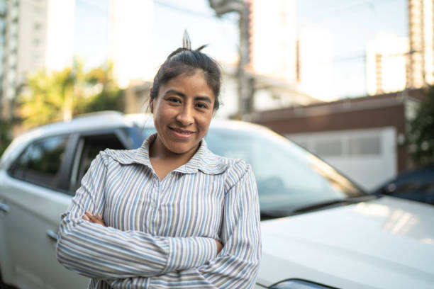 Woman standing with arms crossed in front of a car in the street Woman standing with arms crossed in front of a car in the street peru woman stock pictures, royalty-free photos & images