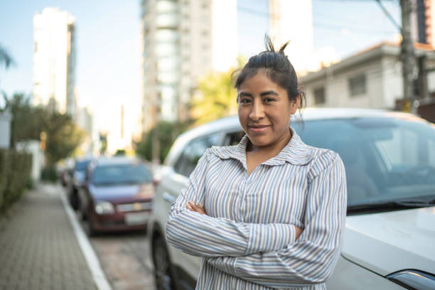 Woman standing with arms crossed in front of a car in the street Woman standing with arms crossed in front of a car in the street peru woman stock pictures, royalty-free photos & images