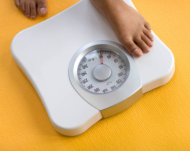 Woman stepping on a scale to weigh herself stock photo