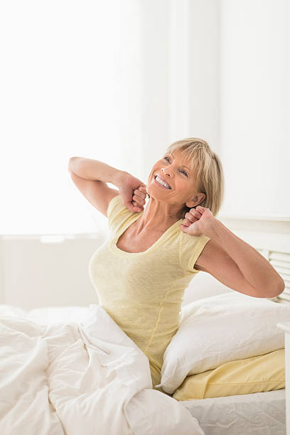 Woman Stretching While Sitting In Bed stock photo