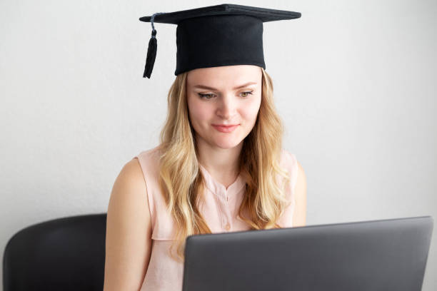 Woman student takes an online exam, defends a diploma behind a laptop. Online education, graduation concept Woman student takes an online exam, defends a diploma behind a laptop. Online education, graduation concept. bachelor degrees stock pictures, royalty-free photos & images