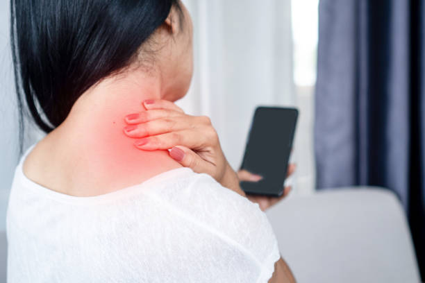 woman suffering from neck , shoulder pain using mobile phone too long with bad posture stock photo
