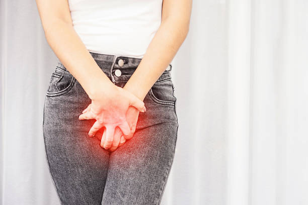 woman suffering from pain, itchy crotch hand holding her burning vaginal caused by bladder infections or cystitis stock photo