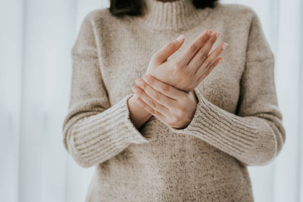 Woman suffering from wrist pain Cropped shot of woman in sweater holding her wrist pain inflammation stock pictures, royalty-free photos & images