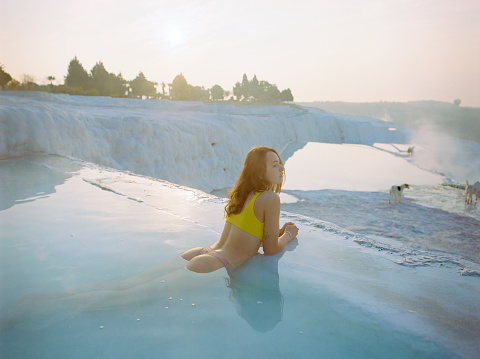 Young Caucasian woman swimming in travertine pool in Pamukkale