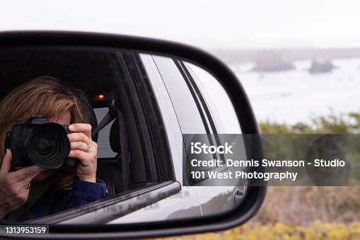 istock Woman taking a picture of self in car side rear view mirror 1313953159