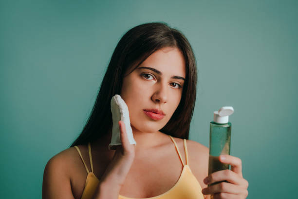 Woman taking off make-up with micellar water and a reusable cotton pad stock photo