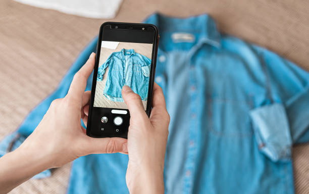 スマートフォンでデニムシャツの写真を撮る女性 - ゼロ・ウェイスト 写真 ストックフォトと画像