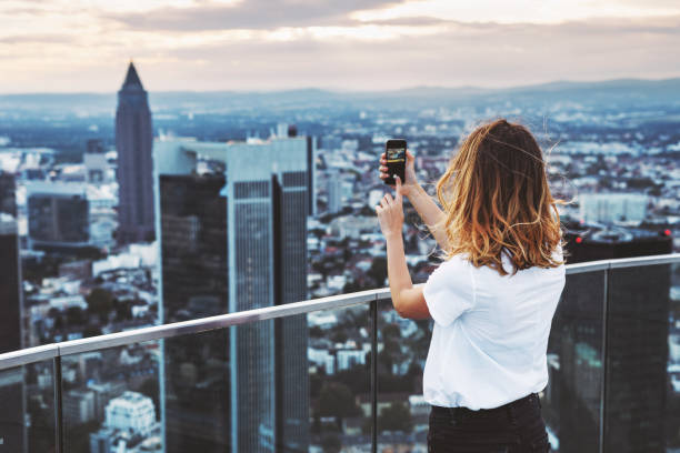 Woman taking photo with mobile phone above city Young woman takes photo with mobile phone above Frankfurt, Germany hesse germany stock pictures, royalty-free photos & images