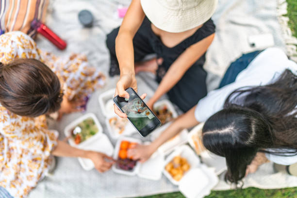 Woman taking photos and videos of food during picnic while preparing food stock photo
