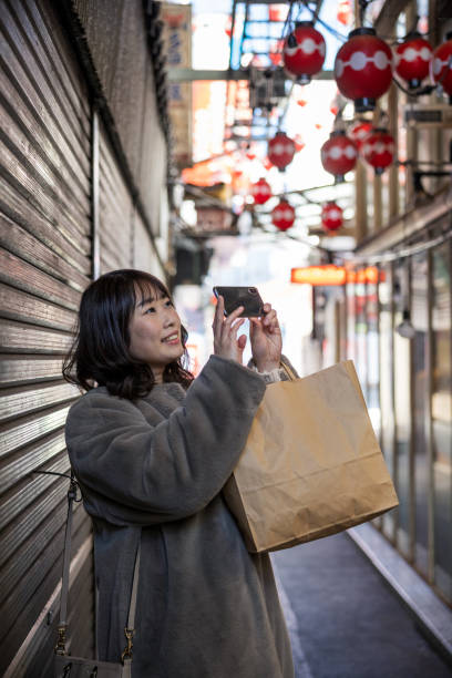 Woman taking photos in narrow shopping street Woman visiting city to enjoy solo time. Having lunch, shopping, walking in town and public park. how do you say shut up in japanese stock pictures, royalty-free photos & images