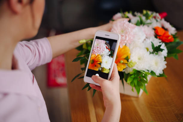 Woman taking picture flower composition on smartphone stock photo