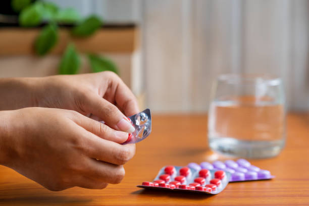Woman Taking Pills or Medicine A female person taking medicines or antibiotic tablets with a glass of water. Concept for sick at home treatment and medication, covid-19 immunity booster, vitamins. generic drug stock pictures, royalty-free photos & images