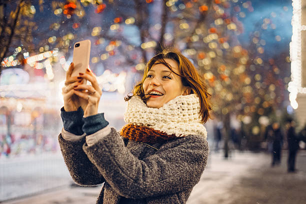 woman taking selfies on the christmas decorated street - smartphone christmas imagens e fotografias de stock