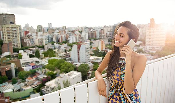 Woman talking at phone. Smiling woman talking on the phone on the rooftop with beautiful view indian women walking stock pictures, royalty-free photos & images