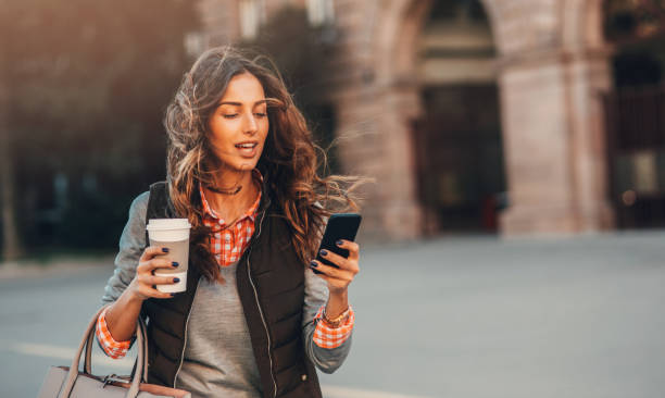 vrouw texting en drinken koffie buiten. - walking with coffee stockfoto's en -beelden