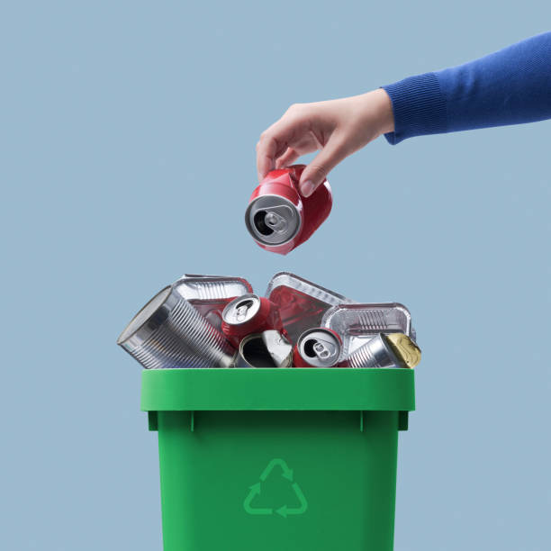 Woman throwing a can in the recycling bin stock photo
