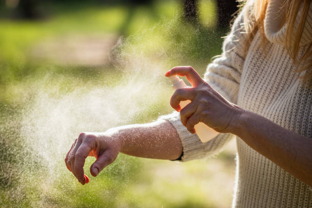 Woman tourist applying mosquito repellent on hand during hike in forest Insect repellent. Woman tourist applying mosquito repellent on hand during hike in nature. Skin protection against tick and mosquito bite  bug repellant stock pictures, royalty-free photos & images