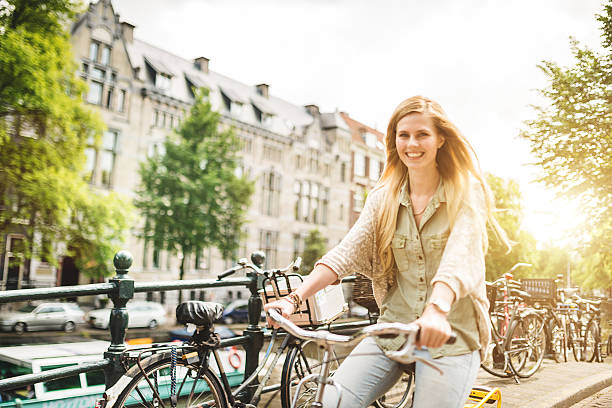 woman tourist cycling on amsterdam - zomer nederland stockfoto's en -beelden