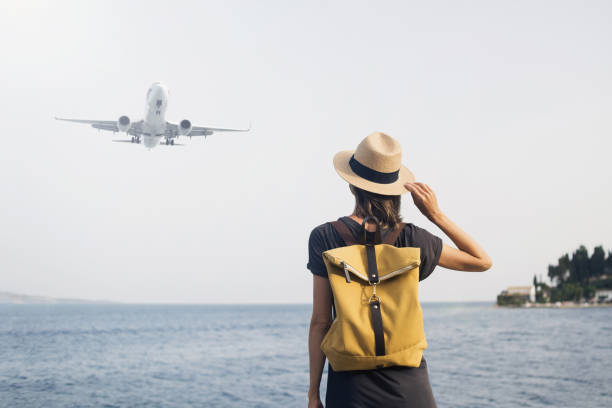 Woman tourist looking at flying plane. Travel concept stock photo