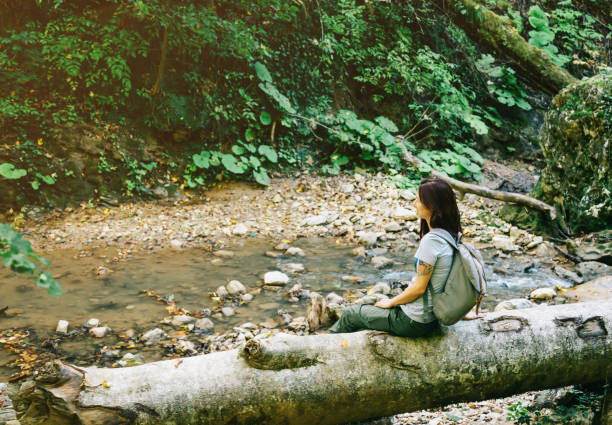 Woman tourist with a backpack is resting near creek. stock photo