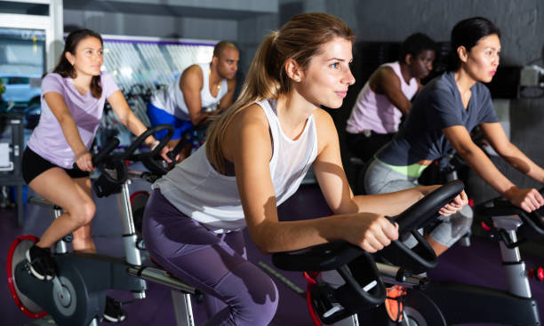 Woman training on stationary bike in gym stock photo