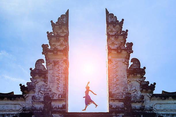 Woman traveler jumping with energy in gate temple, Bali, Indonesia Woman traveler jumping with energy and vitality in the gate of a temple, Bali, Indonesia indonesian girl stock pictures, royalty-free photos & images