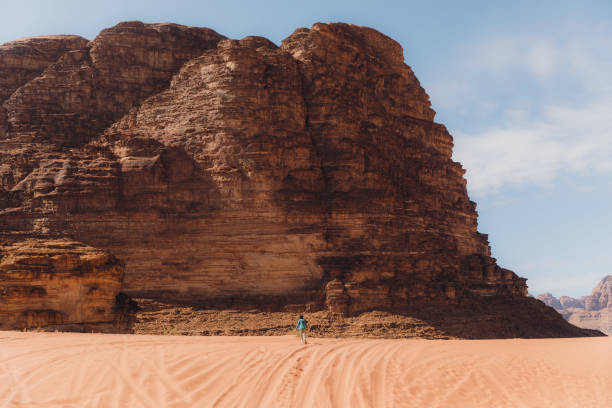 Woman traveler walking the picturesque remote desert enjoying the view at Wadi Rum Young female explorer running the sands contemplating the scenic views of the mountains and red desert in Jordan hot middle eastern women stock pictures, royalty-free photos & images
