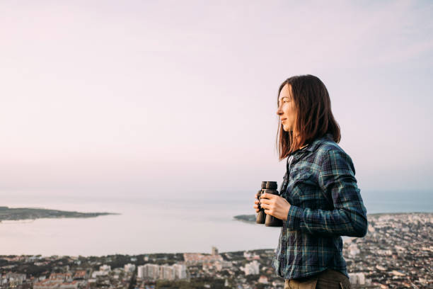 Woman traveler with binoculars on background of sky. stock photo