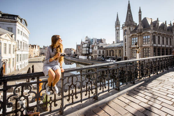 Woman traveling in Gent old town, Belgium Young woman tourist sitting on the bridge in the old town of Gent city durnig the sunrise in Belgium flanders belgium stock pictures, royalty-free photos & images