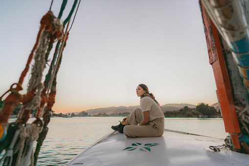 Young Caucasian woman traveling on felucca on the Nile at sunset