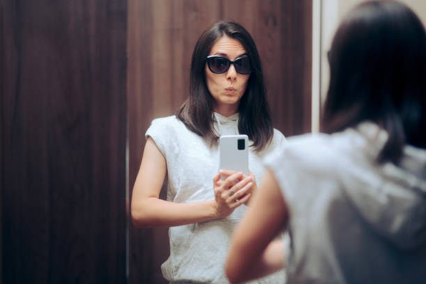 Woman Trying on Outfit Taking a Selfie in a Changing Room Mirror Funny girl checking her new clothes while posting on social media snob stock pictures, royalty-free photos & images