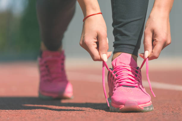 Woman tying laces of running shoes before training stock photo